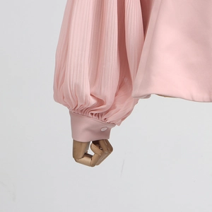 Detail of pink pleated chiffon sleeve with elegant button cuff on a wooden mannequin arm