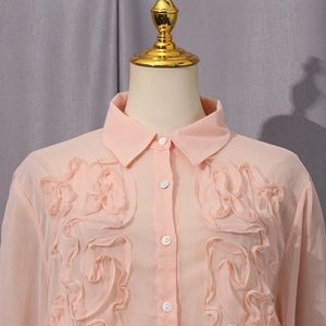 Detail of light pink long sleeve shirt featuring decorative 3D floral pleated accents