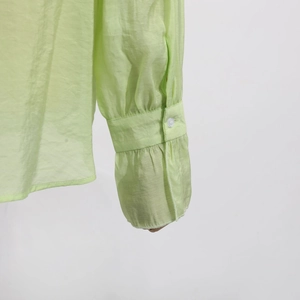 Detailed close-up of light green blouse cuffs with ruffle details and button closure