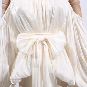 Detail of off-white pleated satin blouse with oversized waist bow and lantern sleeves