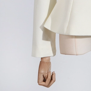 Detail of ruffle cuffs and hem on cream tweed jacket with rich woven texture