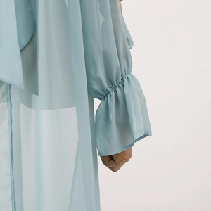 Detail of light blue chiffon fabric with ruffled sleeves and necktie on a mannequin