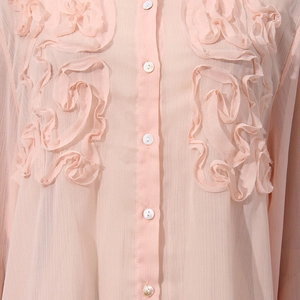 Close-up of pink chiffon blouse featuring 3D floral pleated details and pearl buttons