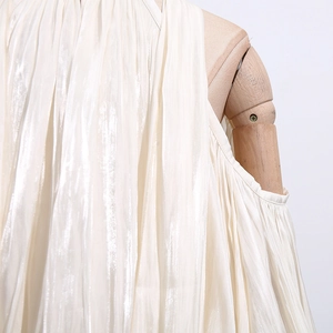 Detail of elegant pleated off-shoulder top with halter neck tie and silky fabric texture
