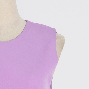 Detail of round neckline and lilac fabric texture on a sleeveless ostrich feather top