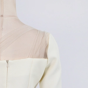 Detailed close-up of cream white woven fabric and mesh patchwork with invisible zipper