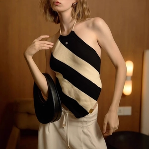 Detail of knitted halter neck top featuring black and white diagonal stripes and metal logo