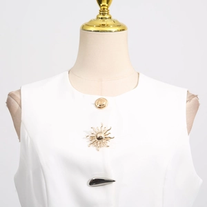 Detail of white sleeveless top showing round neck and artistic gold irregular buttons