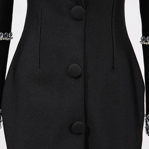 Détail de la robe blazer noire cintrée avec des poignets ornés de strass brillants