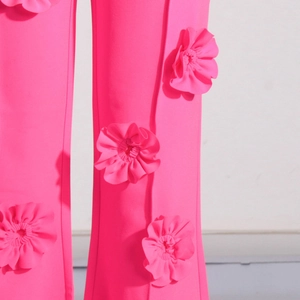 Dettaglio ravvicinato dei pantaloni rosa con applicazioni floreali 3D e tessuto strutturato