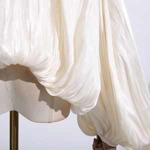 Macro shot of pearl white pleated fabric texture on chic lantern sleeve blouse