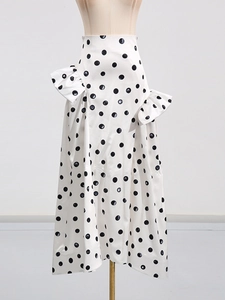 Jupe mi-longue blanche à pois noirs, taille haute et détails de plis élégants