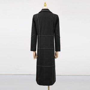 Detail of black trench coat with white contrast grid stitching and buttoned cuffs