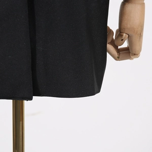 Détail de l'ourlet de robe noire montrant une texture côtelée et une couture de qualité