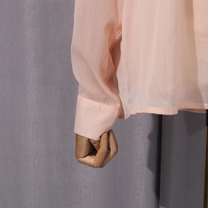 Detail of sheer peach chiffon blouse showing translucent fabric texture and sleeve cuff