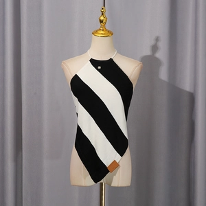 Detail of knit halter top with diagonal stripes, metal logo, and asymmetric hemline