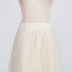 Detail of high-waist elastic waistband and layered tulle on a beige midi skirt