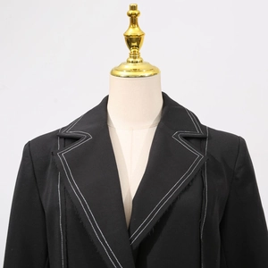Detail of contrast white stitching and raw edge finish on a black slim long trench coat