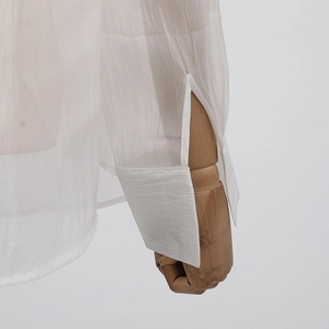 Détail de poignets de chemise blancs translucides avec fente et texture plissée fine