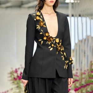 Detail view of ornate gold floral appliques on black deep U-neck tailored blazer