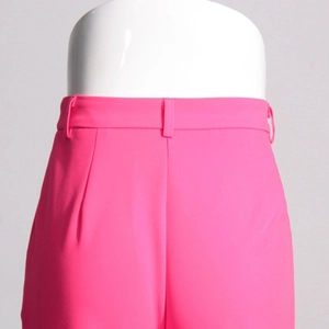 Dettaglio dei pantaloni a vita alta rosa shocking con passanti e pieghe sartoriali