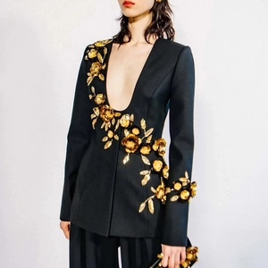 Close-up of golden floral embroidery and 3D flower appliques on a black fitted blazer