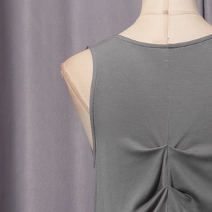 Detailed view of the V-shaped pleated design and knitted texture on back of dark grey vest