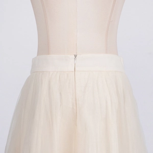 Detailed view of the invisible zipper and multilayer mesh fabric of the beige tulle skirt