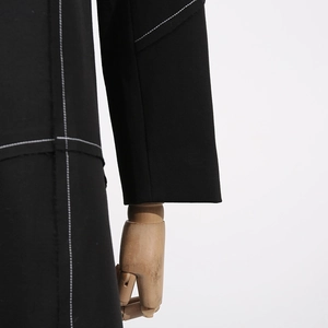 Detail of black trench coat sleeve with contrast white stitching on premium fabric