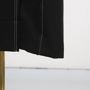 Close-up of contrast white stitching details on the edge of a premium black trench coat