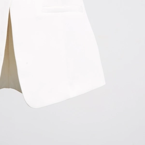 Detailed macro view of the white vest showing fine stitching and rounded hem design