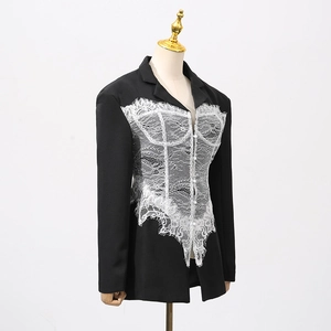 Detail of elegant black blazer featuring intricate white lace patchwork on the front panel