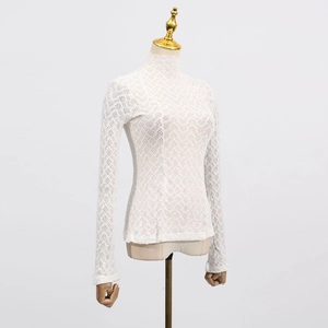 Detailed view of the intricate floral lace texture and hollow out pattern on a white top