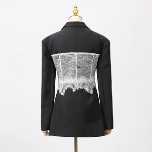 Detail of corset-style white lace back panel on a sleek black long-sleeve blazer