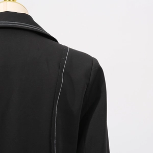 Close-up of contrast white stitching on a black long trench coat collar and shoulder
