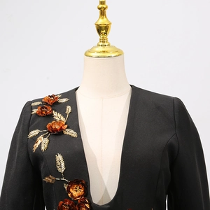 Detail of handmade gold sequin and bead flower embroidery on a black blazer's shoulder