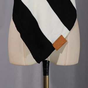 Close-up of black and white striped knit fabric with a brown leather decorative logo patch