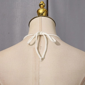Close-up of white knitted halter tie tied in a bow on a mannequin for stylish summer top