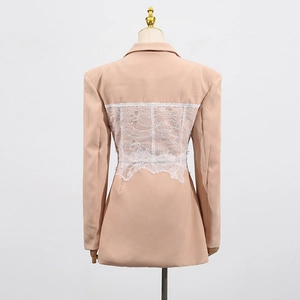 Detail view of the back of a pink blazer featuring intricate white lace floral patchwork