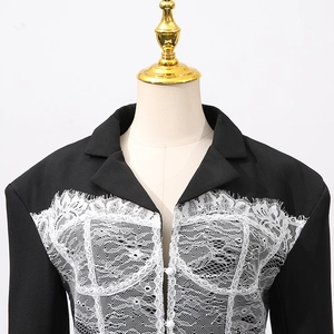 Detail of delicate white eyelash lace patchwork on a slim black blazer with buttons