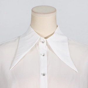 Detailed close-up of white dress with oversized lapel collar and rhinestone buttons
