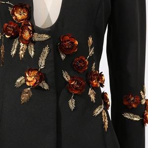 Detailed close-up of intricate bronze floral beadwork and sequins on a black blazer