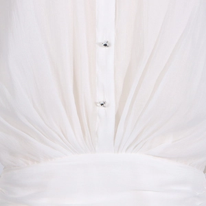 Detail of white mesh dress featuring pleated fabric and silver rhinestone buttons