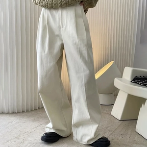 Detail of high-waist cream wide-leg trousers with elegant front pleat and crisp texture