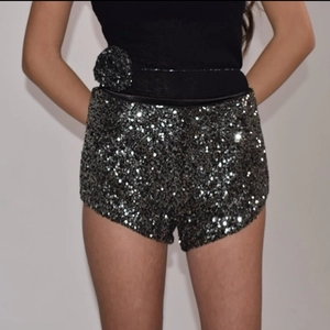 Detail der hoch taillierten schwarzen Pailletten-Shorts mit dekorativer Stoffblumenverzierung