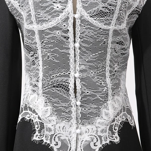 Detail of delicate white eyelash lace patchwork and buttons on a black slim blazer