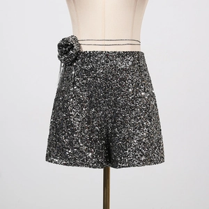 Detail der silbernen Pailletten-Shorts mit 3D-Rose und schmalem Metallgürtel am Bund
