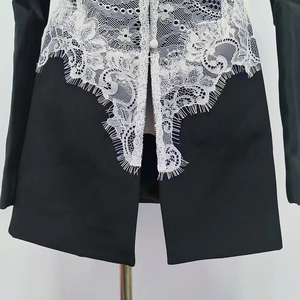 Close-up of contrast black blazer with delicate white lace patchwork and button detail