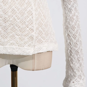 Close-up of the delicate white lace texture and diamond crochet pattern of the slim-fit top
