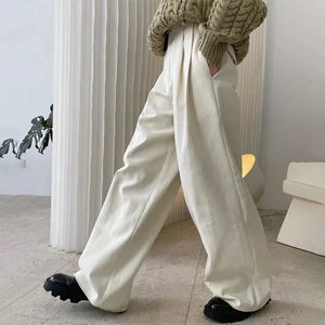 Detail of high-waisted cream wide-leg trousers with sharp pleats and elegant drape